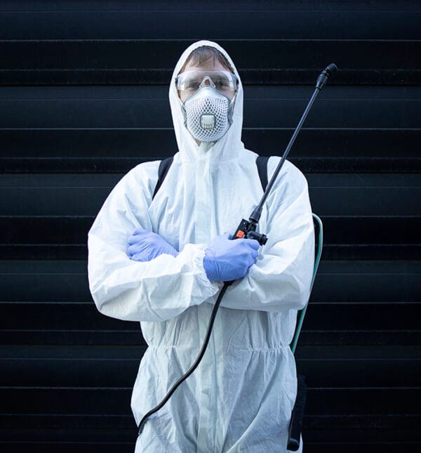 Person in white chemical protection suit holding sprayer with di