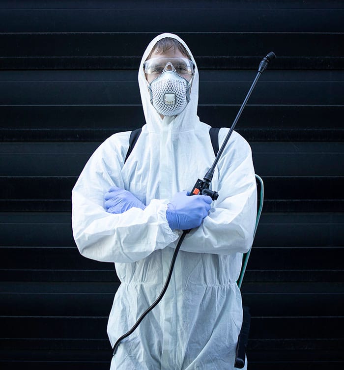 Person in white chemical protection suit holding sprayer with di
